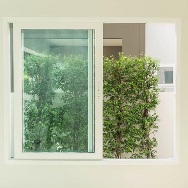 Ventana corrediza blanca con vista a jardín exterior.