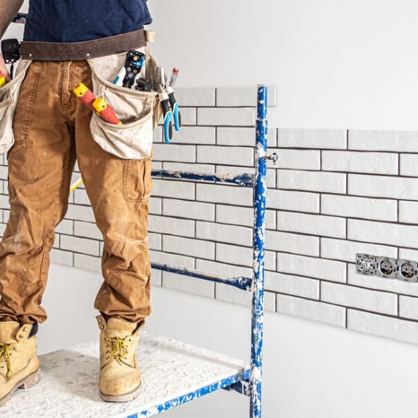 Colocación de azulejos en pared durante reforma de cocina. Reformas de cocinas